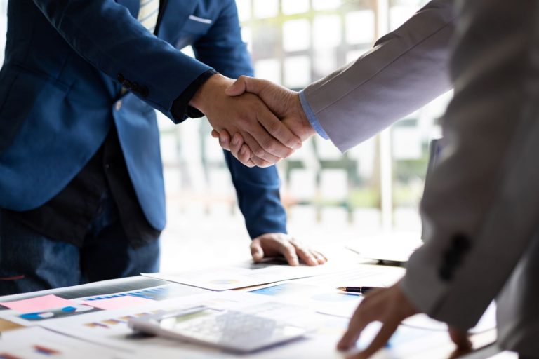 closeup of people in suits shaking hands after a deal